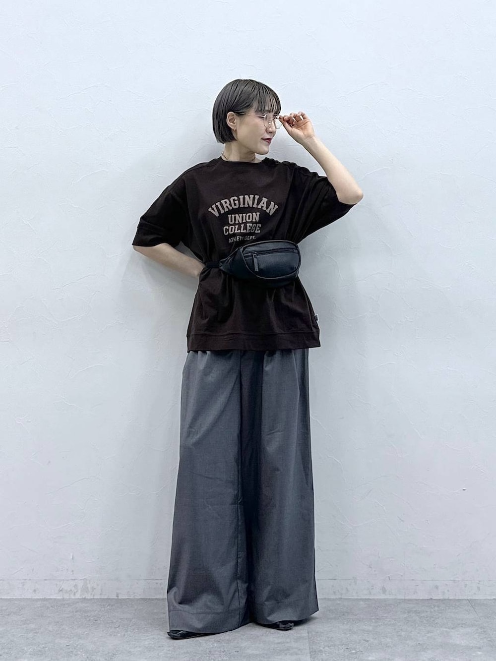 ブラウン系のTシャツ/カットソー、ブラック系のボディバッグ/ウエストポーチ、グレー系のスラックスを着用したレディースの春コーディネートの2枚目の写真