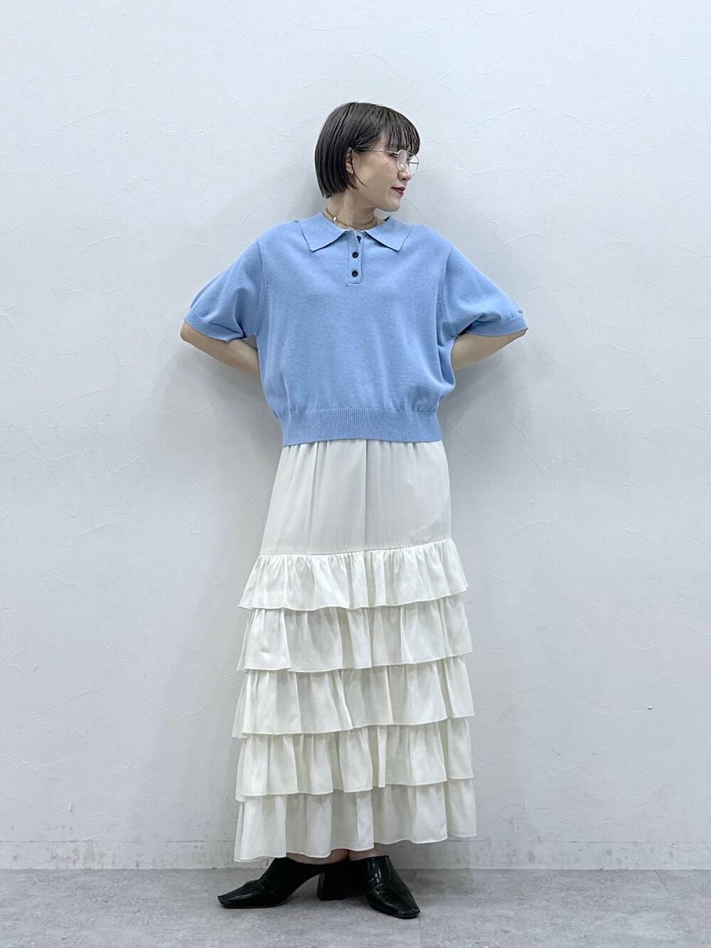 ブルー系のポロシャツ、ホワイト系のスカートを着用したレディースの春コーディネートの3枚目の写真