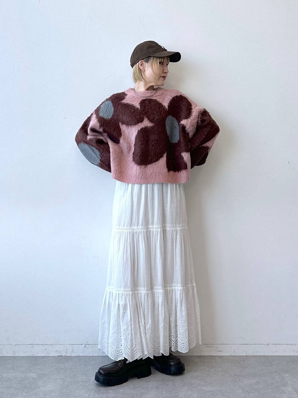 ブラック系のローファー、ピンク系のニット/セーター、ホワイト系のスカートを着用したレディースの秋コーディネートの2枚目の写真