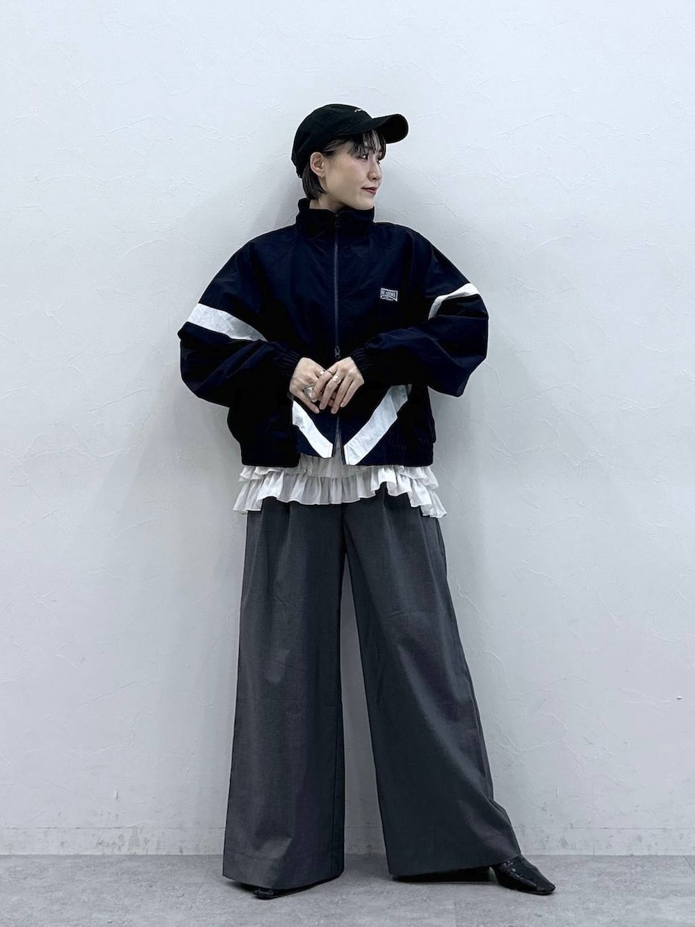 ホワイト系のキャミソール、ブルー系のブルゾン、グレー系のスラックスを着用したレディースの春コーディネートの5枚目の写真