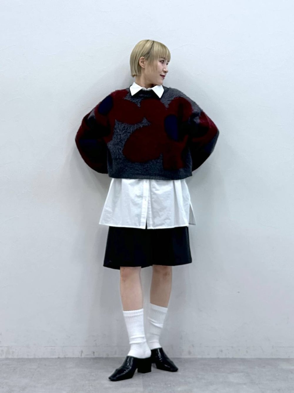 グレー系のニット/セーター、ホワイト系のシャツ/ブラウス、ブラック系のスラックスを着用したレディースの秋コーディネートの2枚目の写真