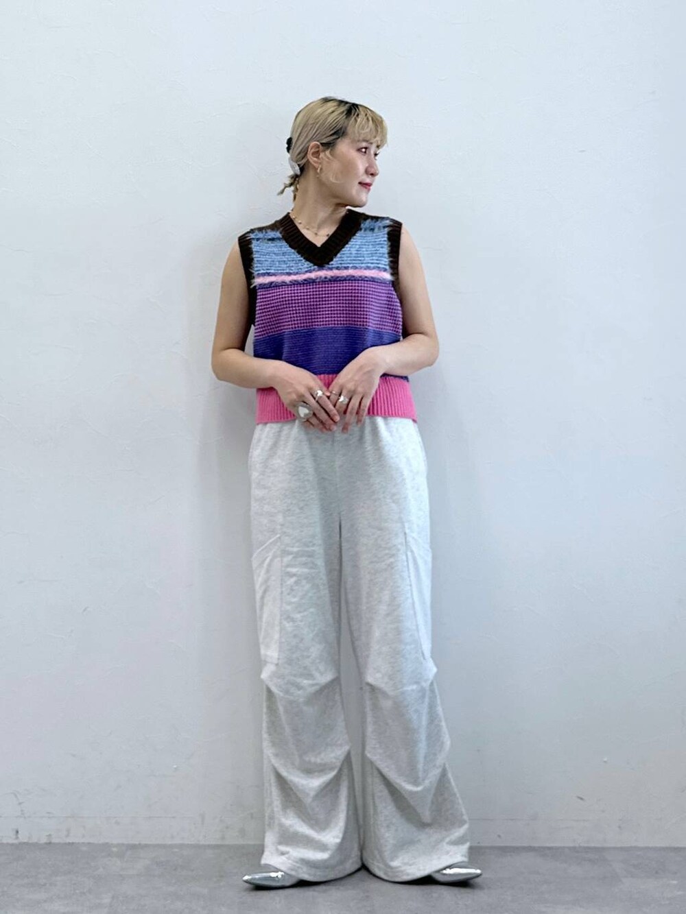 シルバー系のパンプス、ホワイト系のカーゴパンツ、ピンク系のベストを着用したレディースの秋コーディネートの2枚目の写真