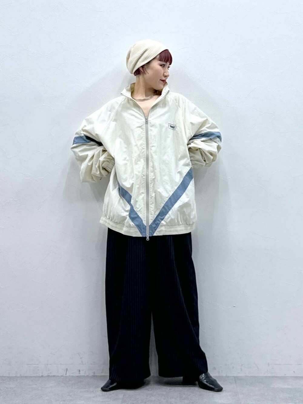 ホワイト系のブルゾン、ブラック系のスラックスを着用したレディースの春コーディネートの3枚目の写真