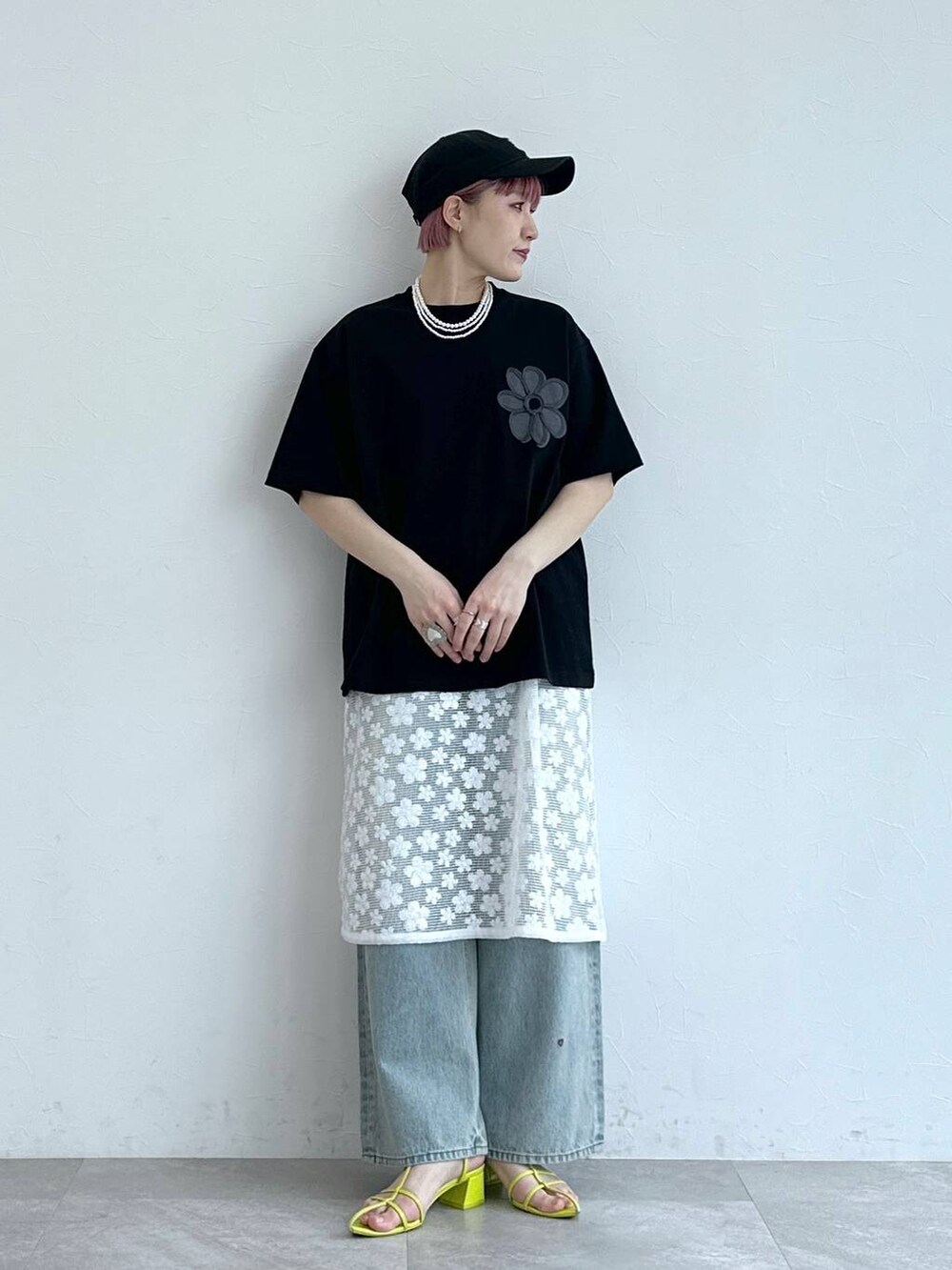 ブルー系のデニムパンツ、ホワイト系のワンピース、ブラック系のTシャツ/カットソーを着用したレディースの春コーディネートの3枚目の写真
