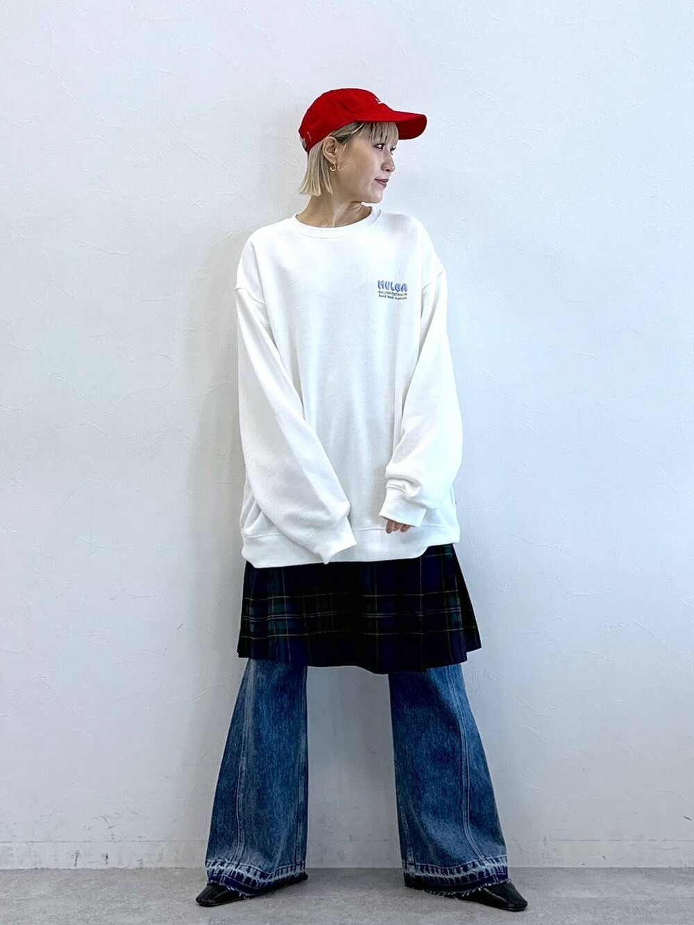 グリーン系のスカート、ブルー系のデニムパンツ、ホワイト系のスウェットを着用したレディースの秋コーディネートの5枚目の写真