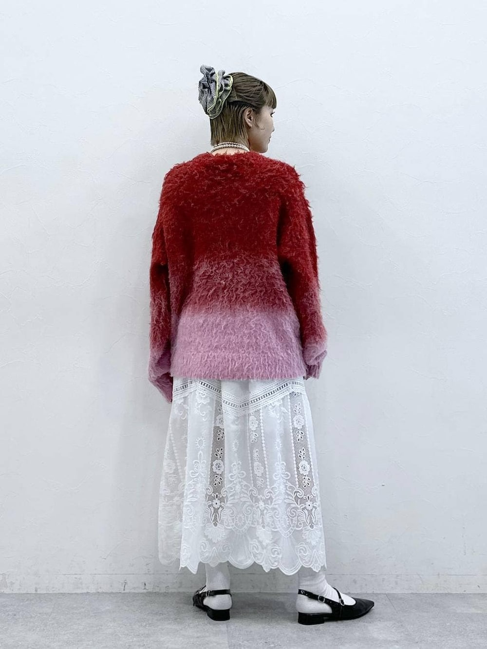 ホワイト系のスカート、レッド系のニット/セーター、ブラック系のパンプスを着用したレディースの冬コーディネートの5枚目の写真