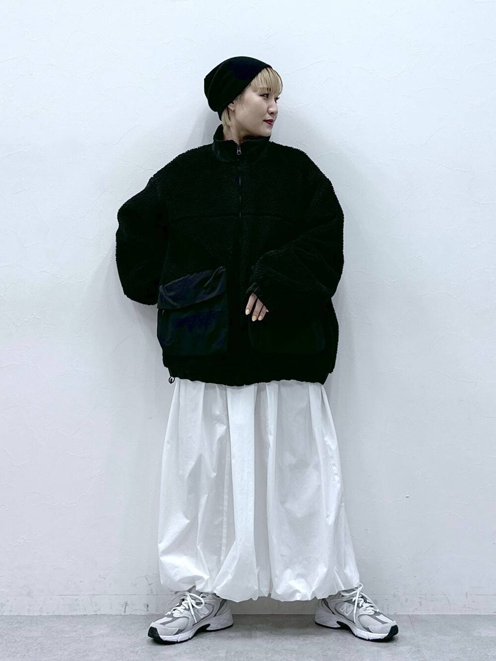 ブラック系のブルゾン、ホワイト系のスカートを着用したレディースの冬コーディネートの2枚目の写真