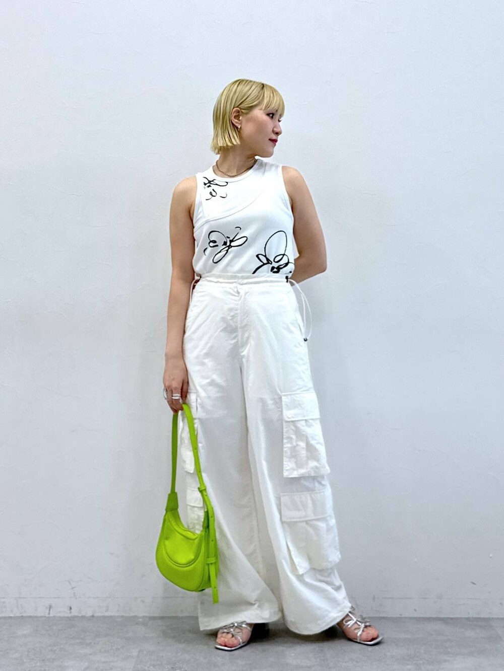 シルバー系のサンダル、ホワイト系のタンクトップ、ホワイト系のカーゴパンツを着用したレディースの夏コーディネートの2枚目の写真