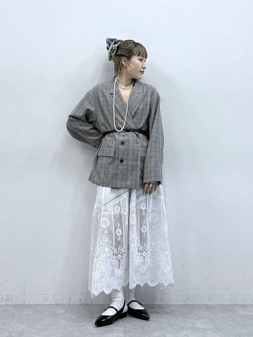 ホワイト系のスカート、ブラック系のパンプス、ベージュ系のテーラードジャケットを着用したレディースの冬コーディネートの2枚目の写真