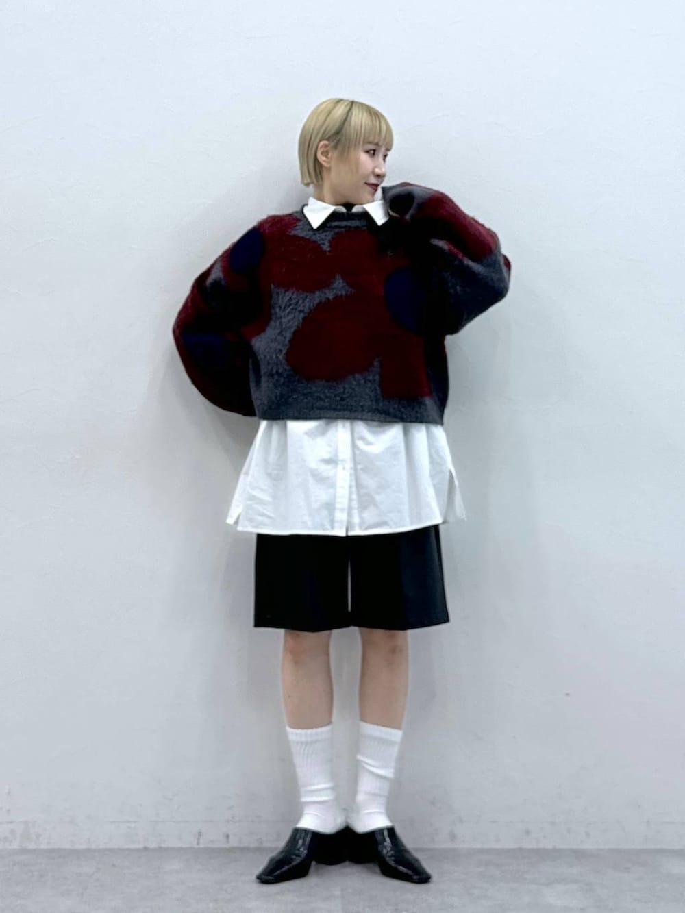 グレー系のニット/セーター、ホワイト系のシャツ/ブラウス、ブラック系のスラックスを着用したレディースの秋コーディネートの3枚目の写真