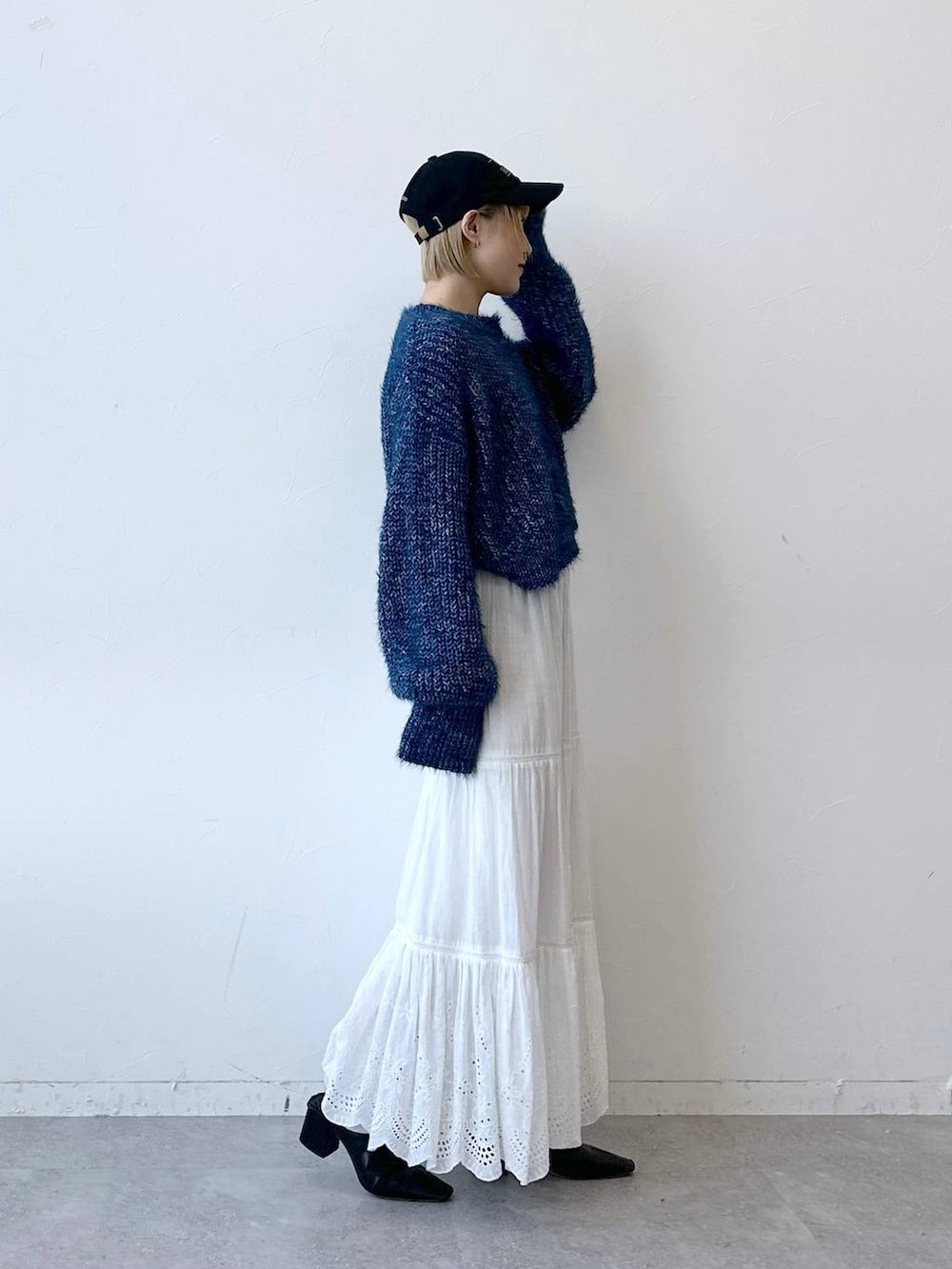 ブルー系のニット/セーター、ホワイト系のスカート、ブラック系のキャップを着用したレディースの秋コーディネートの5枚目の写真