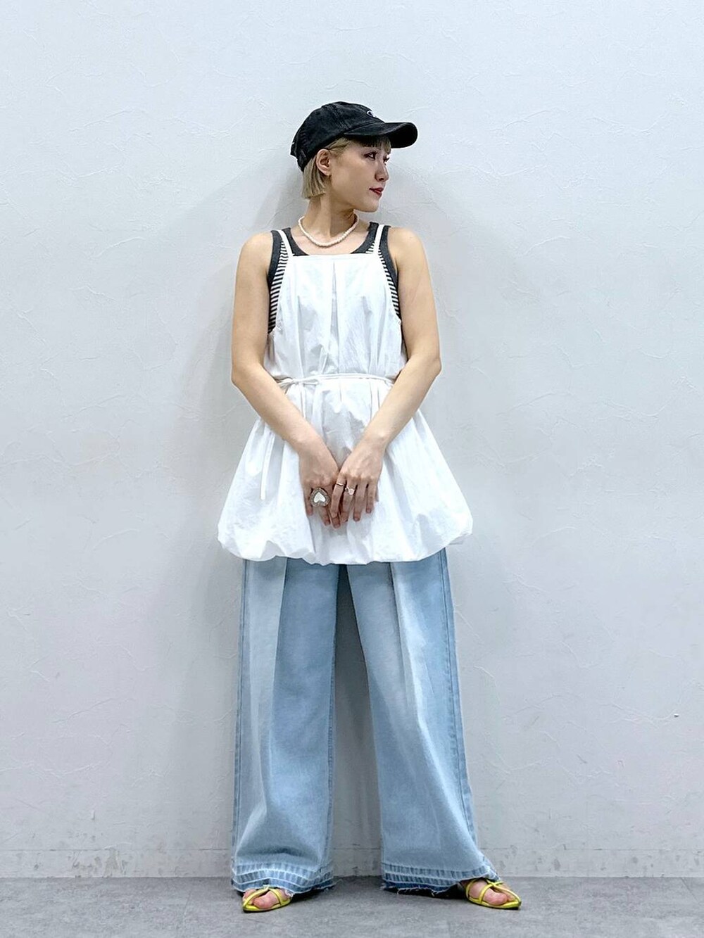 グレー系のタンクトップ、ブルー系のデニムパンツ、ホワイト系のワンピースを着用したレディースの夏コーディネートの2枚目の写真