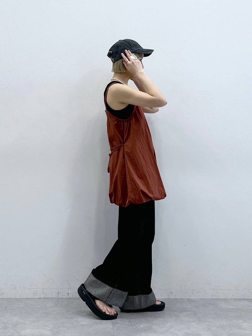 ブラウン系のワンピース、ブラック系のデニムパンツ、ブラック系のキャップを着用したレディースの夏コーディネートの4枚目の写真