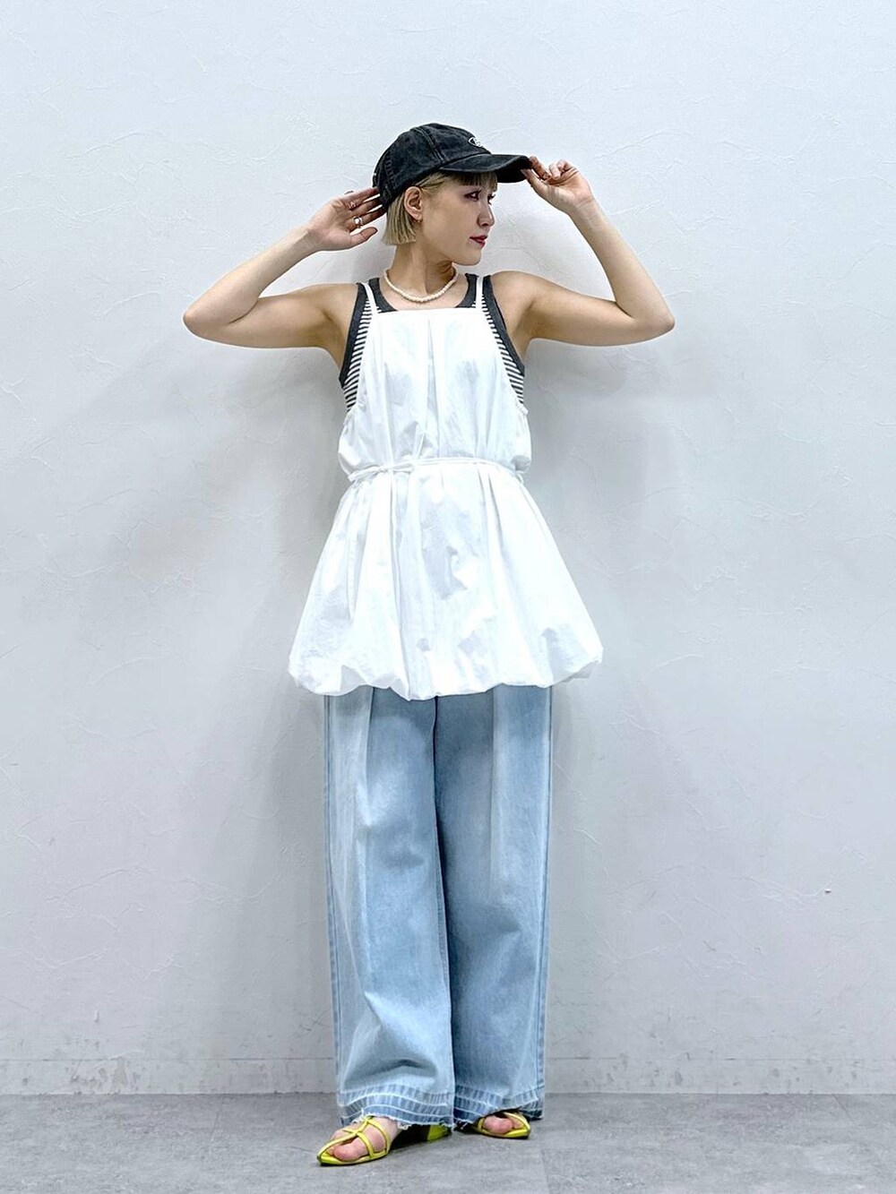 グレー系のタンクトップ、ブルー系のデニムパンツ、ホワイト系のワンピースを着用したレディースの夏コーディネートの3枚目の写真
