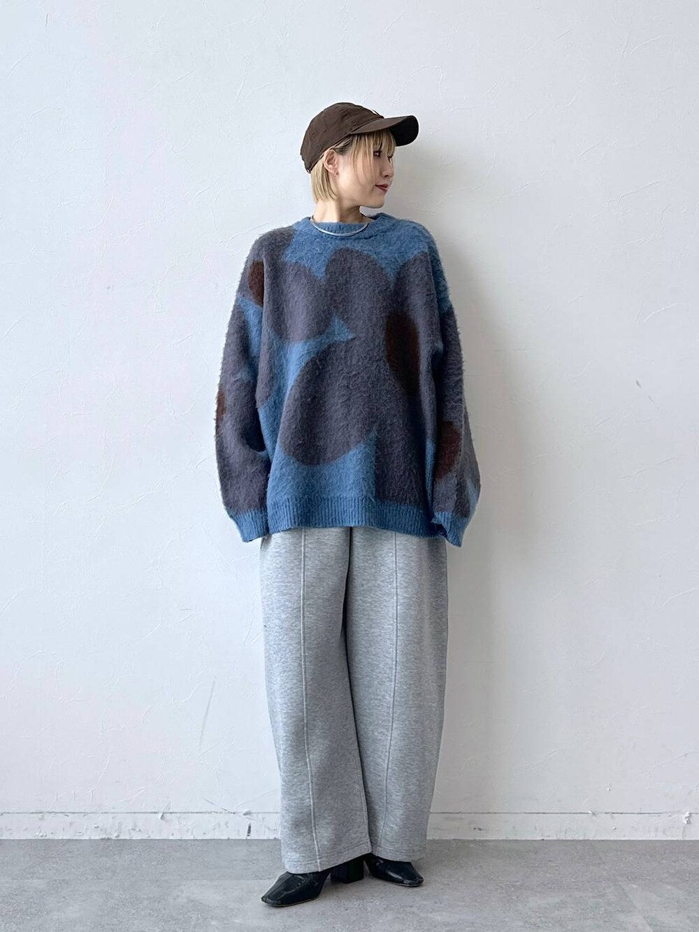 ブルー系のニット/セーター、グレー系のスウェットパンツ、ブラウン系のキャップを着用したレディースの秋コーディネートの3枚目の写真