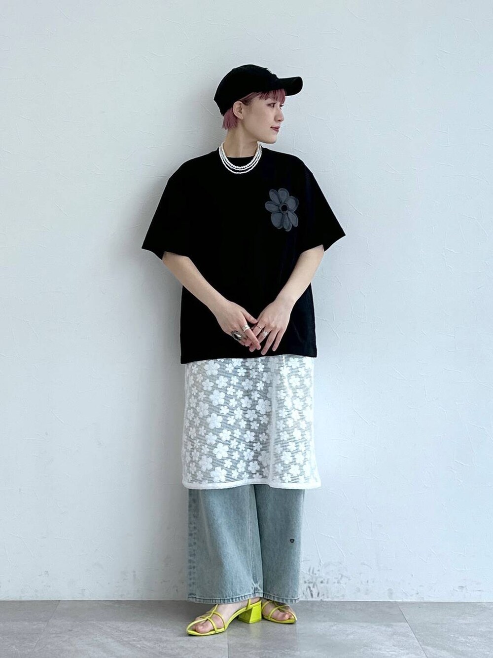 ブルー系のデニムパンツ、ホワイト系のワンピース、ブラック系のTシャツ/カットソーを着用したレディースの春コーディネートの2枚目の写真