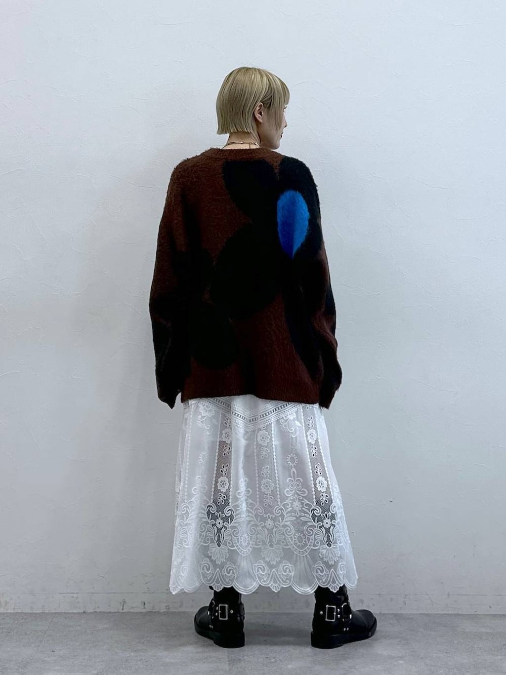 ブラック系のブーツ、ブラウン系のニット/セーター、ホワイト系のスカートを着用したレディースの秋コーディネートの5枚目の写真