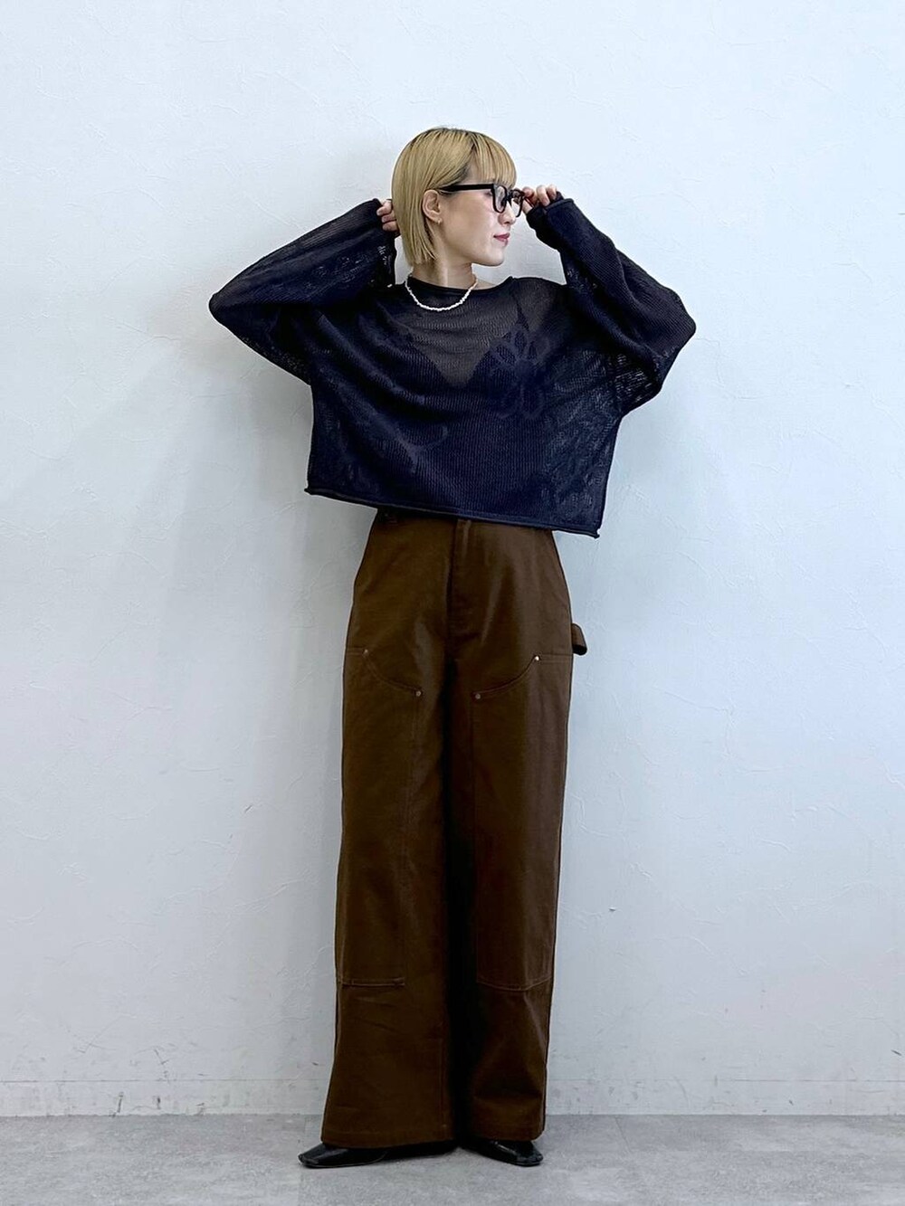 グレー系のニット/セーター、ブラウン系のチノパンツ、グレー系のメガネを着用したレディースの夏コーディネートの3枚目の写真