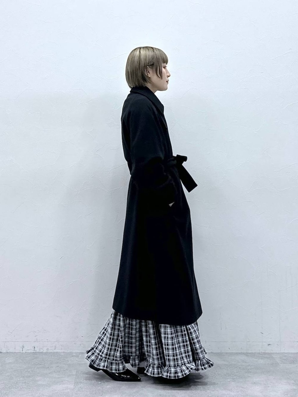 ブラック系のステンカラーコート、ブラック系のスカート、ブラック系のパンプスを着用したレディースの冬コーディネートの5枚目の写真