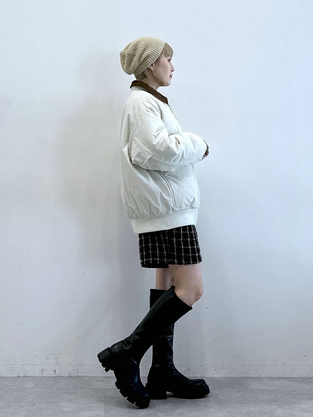 ブラック系のブーツ、ホワイト系のブルゾン、ブラウン系のその他パンツを着用したレディースの冬コーディネートの3枚目の写真