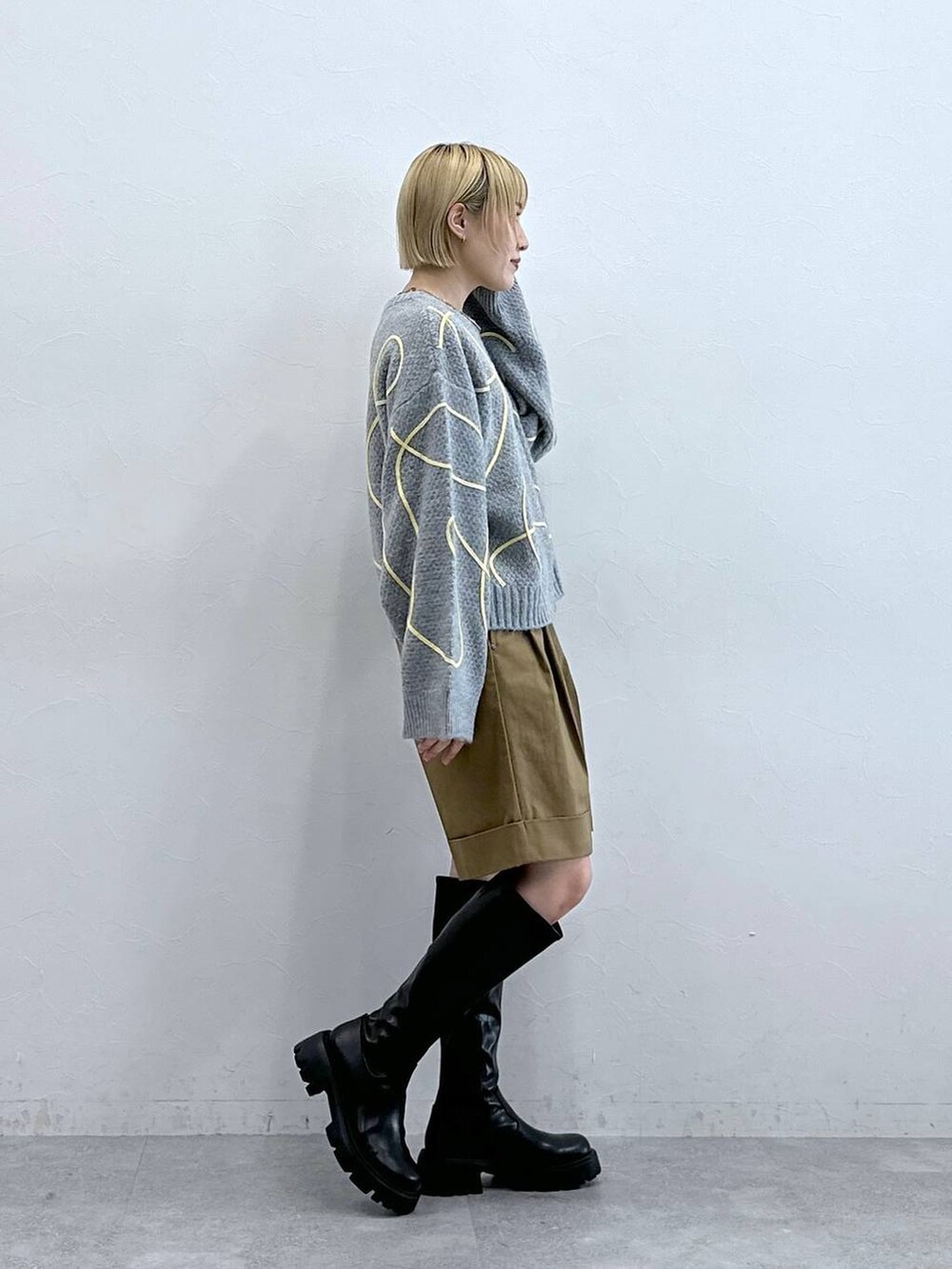 ブラック系のブーツ、ブラウン系のチノパンツ、グレー系のニット/セーターを着用したレディースの秋コーディネートの4枚目の写真