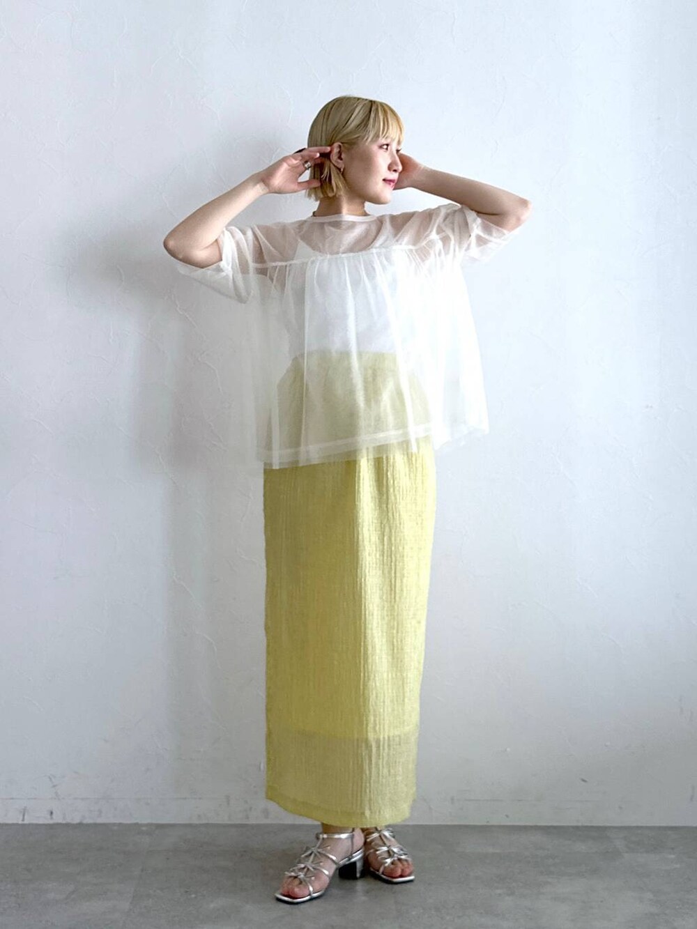 シルバー系のサンダル、イエロー系のスカート、ホワイト系のTシャツ/カットソーを着用したレディースの夏コーディネートの2枚目の写真