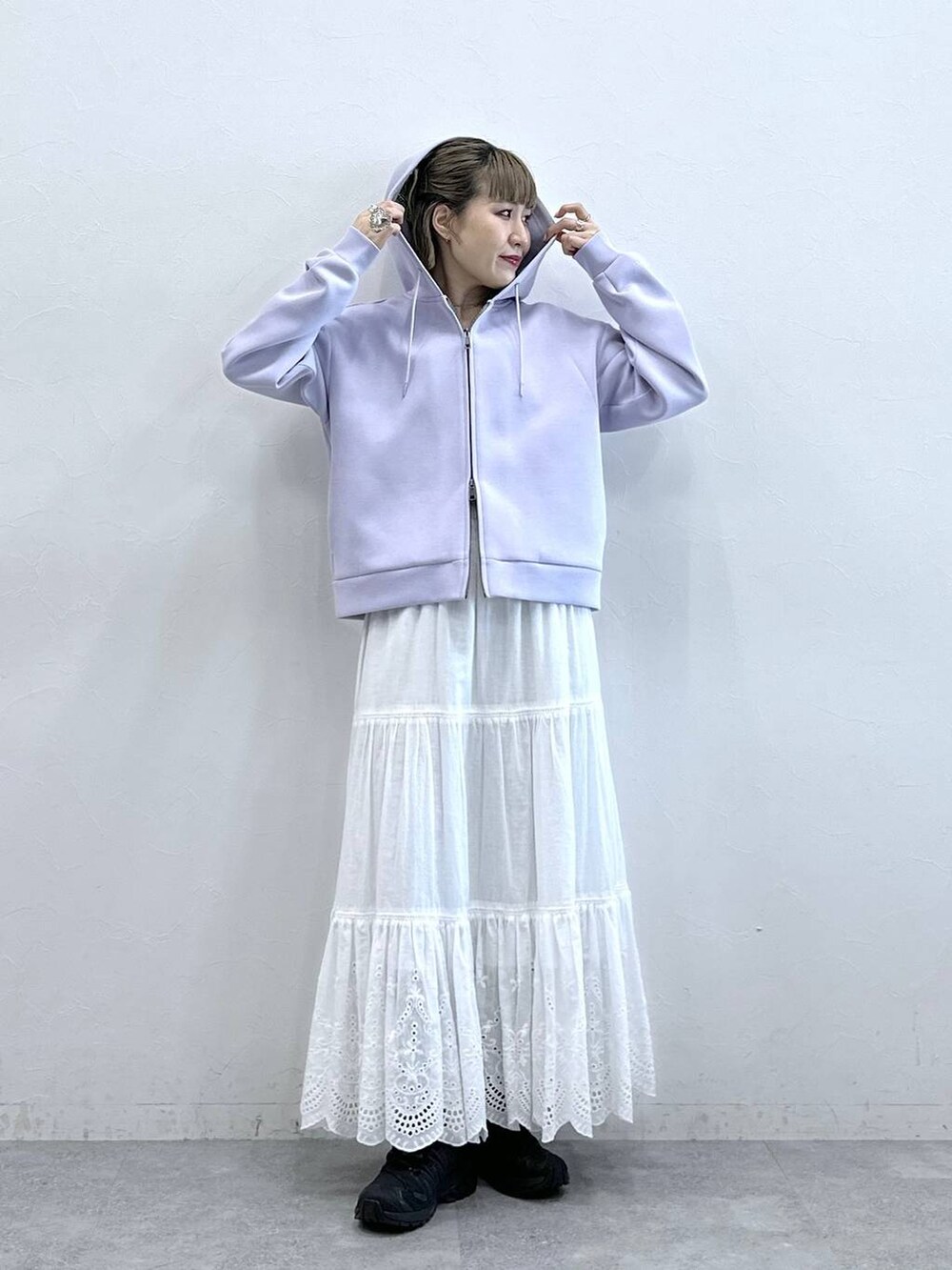 パープル系のパーカー、ホワイト系のスカートを着用したレディースの冬コーディネートの2枚目の写真