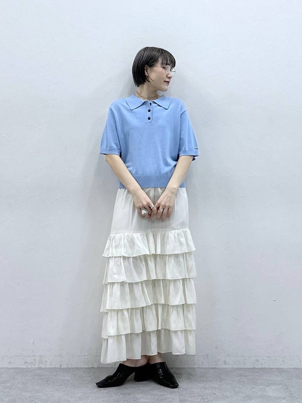 ブルー系のポロシャツ、ホワイト系のスカートを着用したレディースの春コーディネートの2枚目の写真