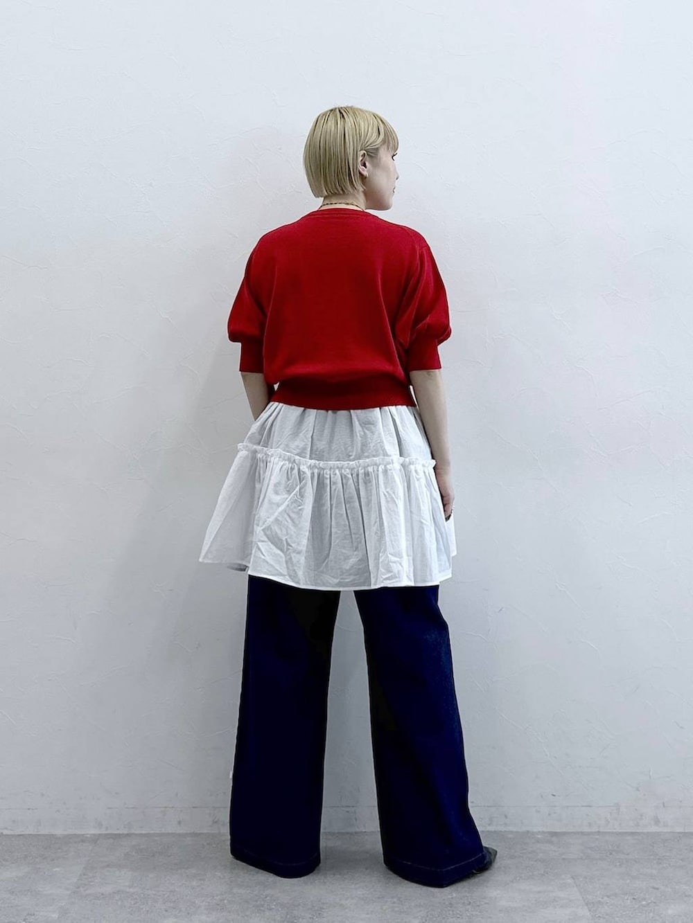 ホワイト系のチュニック、ブルー系のデニムパンツ、レッド系のカーディガン/ボレロを着用したレディースの春コーディネートの5枚目の写真