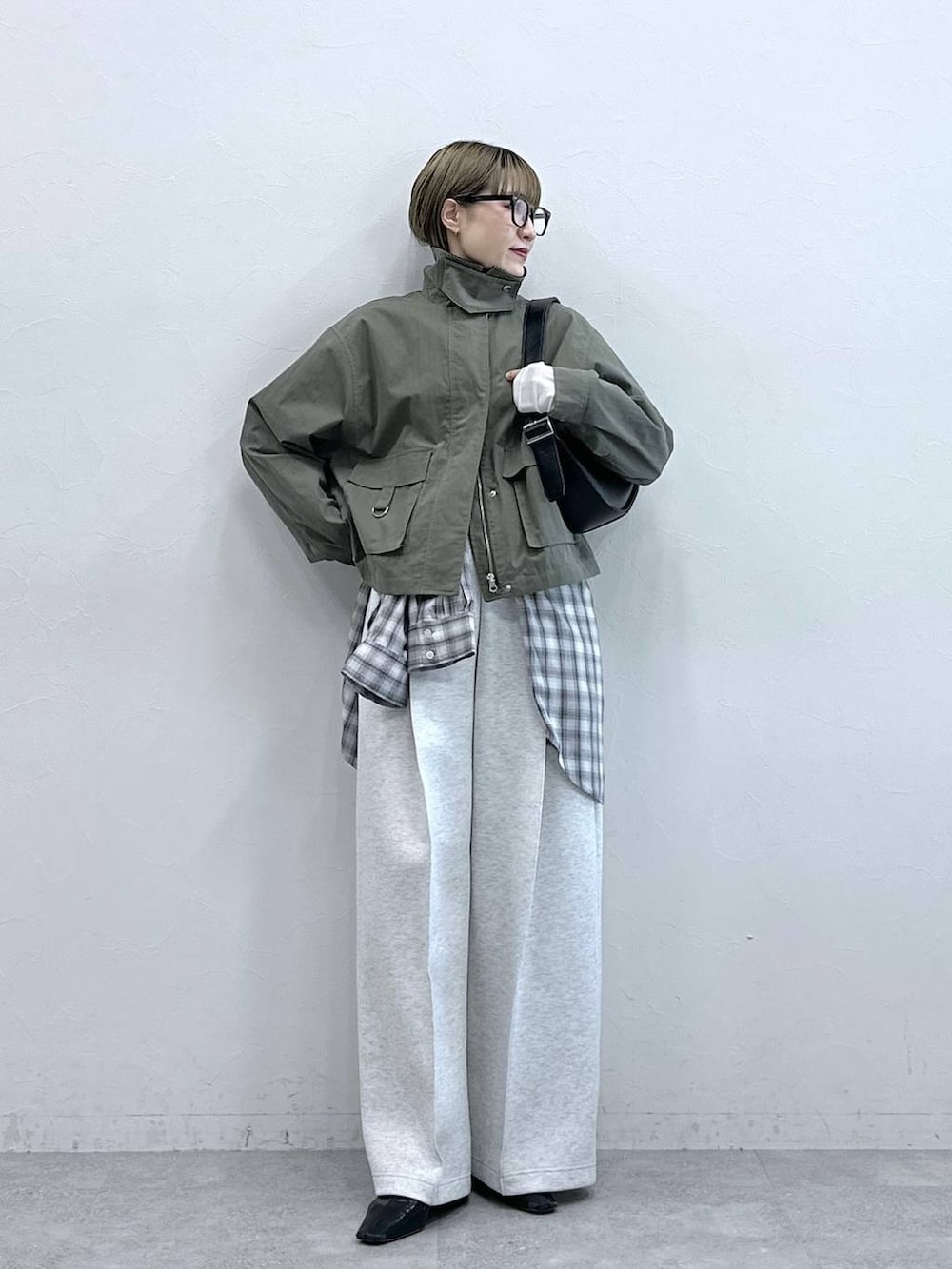 ホワイト系のスウェットパンツ、ブラック系のショルダーバッグ、グリーン系のブルゾンを着用したレディースの冬コーディネートの4枚目の写真