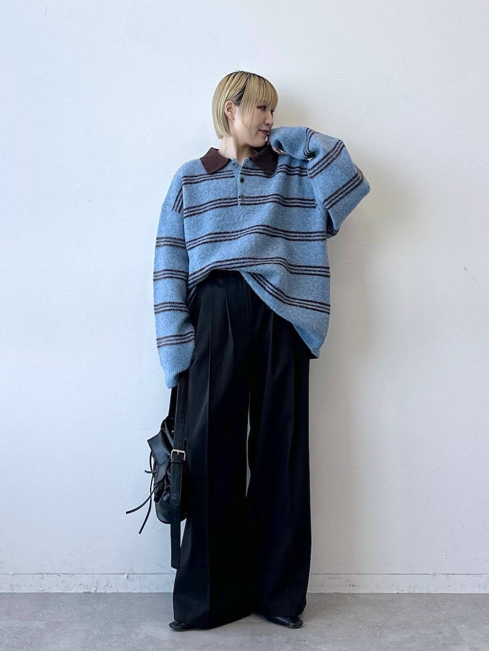 ブラック系のショルダーバッグ、ブラウン系のスラックス、ブルー系のポロシャツを着用したレディースの冬コーディネートの3枚目の写真