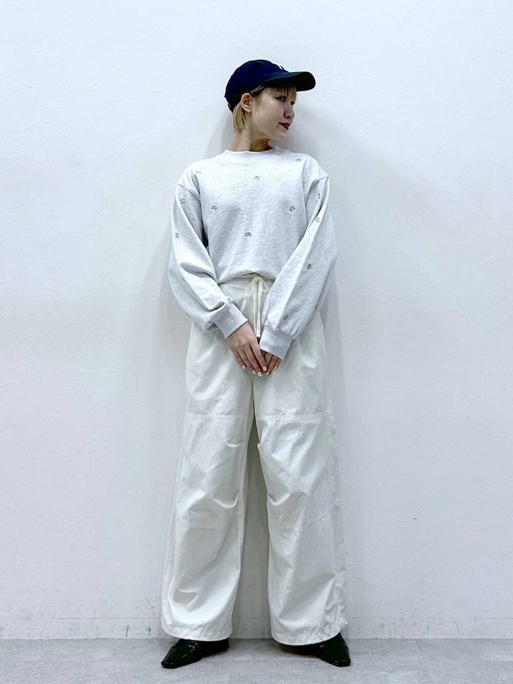 ホワイト系のカーゴパンツ、ホワイト系のスウェット、ブラック系のキャップを着用したレディースの冬コーディネートの6枚目の写真