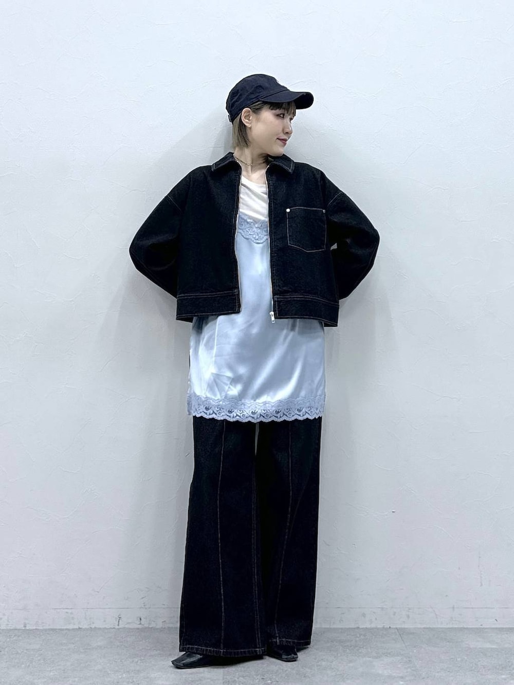 ブラック系のデニムジャケット、ブラック系のデニムパンツ、ブルー系のキャミソールを着用したレディースの冬コーディネートの2枚目の写真