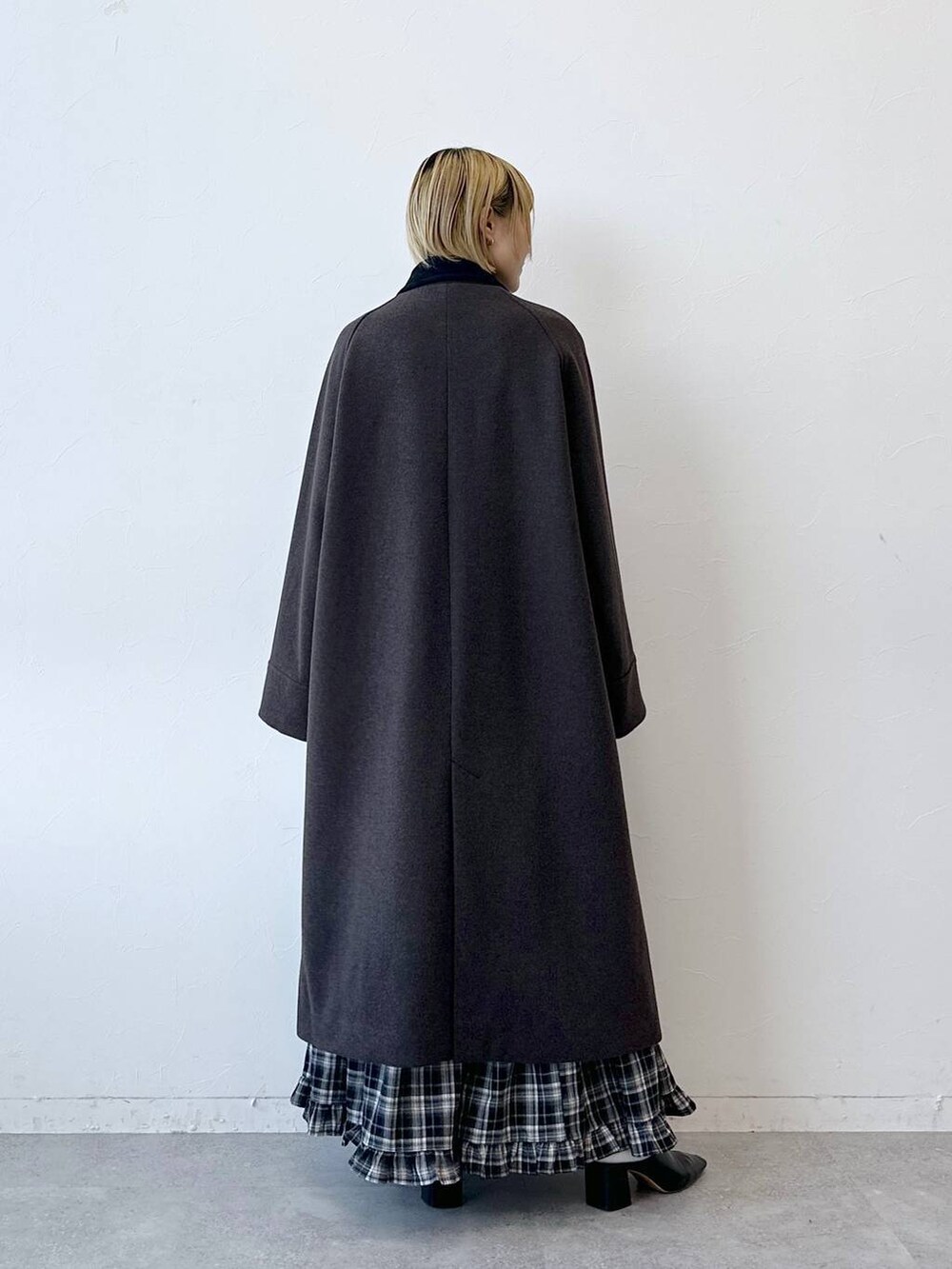 ブラウン系のステンカラーコート、ブラック系のスカートを着用したレディースの冬コーディネートの6枚目の写真