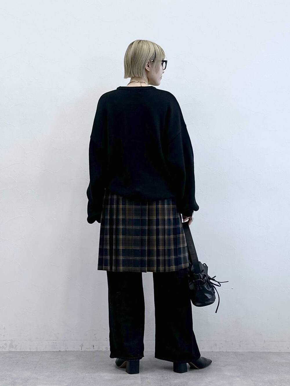 ブラック系のニット/セーター、ブラック系のデニムパンツ、ブラウン系のスカートを着用したレディースの秋コーディネートの5枚目の写真