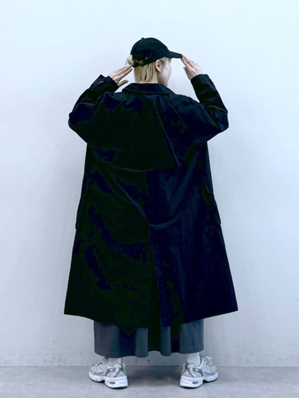 ブラック系のトレンチコート、グレー系のワンピース、ブラック系のキャップを着用したレディースの冬コーディネートの4枚目の写真