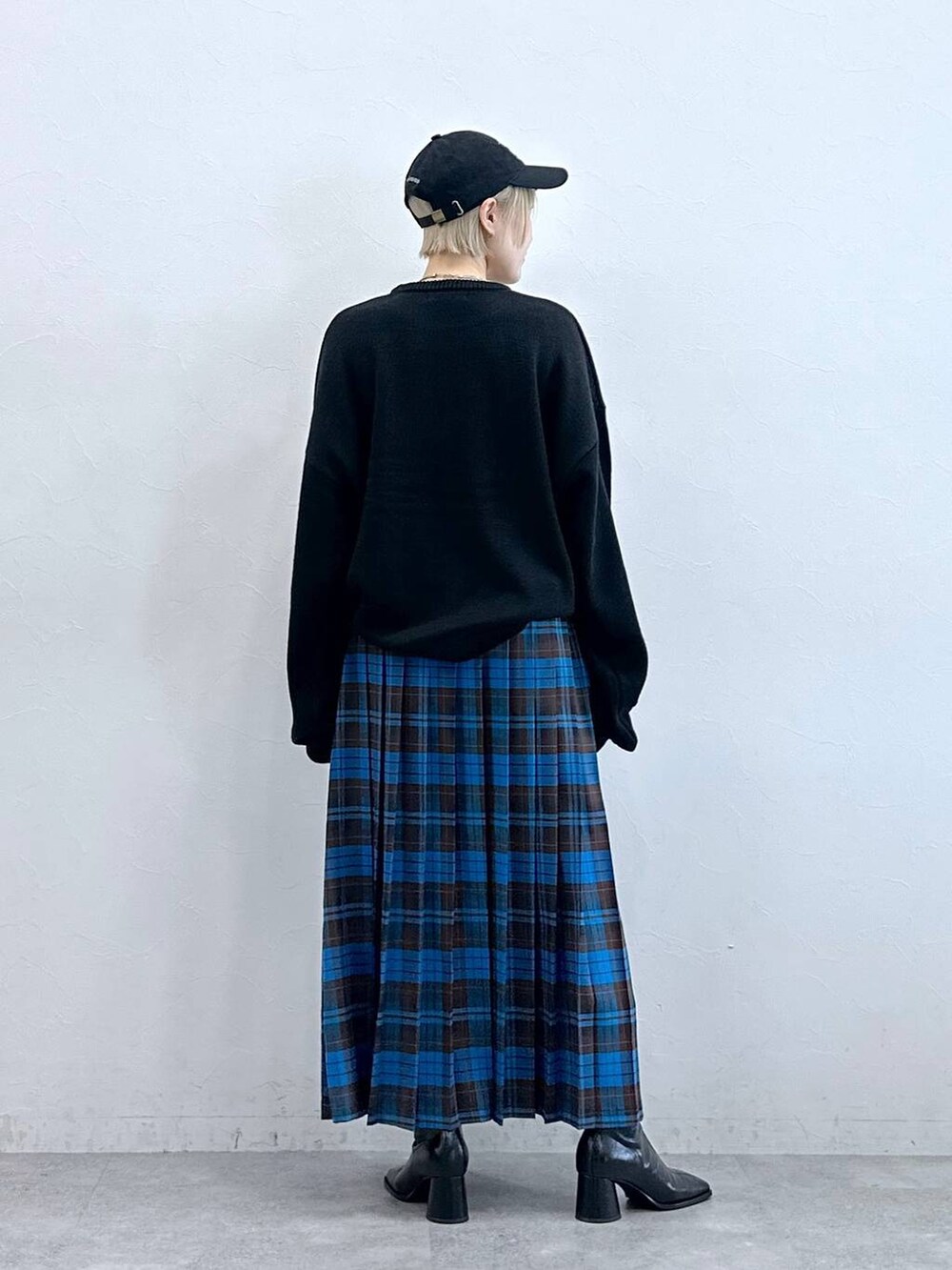 ブラック系のニット/セーター、ブルー系のスカート、ブラック系のキャップを着用したレディースの秋コーディネートの5枚目の写真
