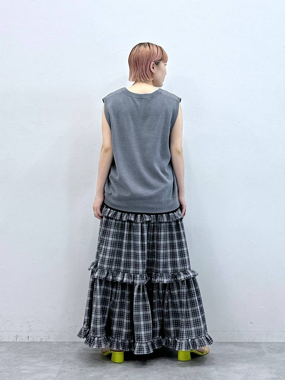 グレー系のベスト、ホワイト系のタンクトップ、ブラック系のスカートを着用したレディースの春コーディネートの6枚目の写真