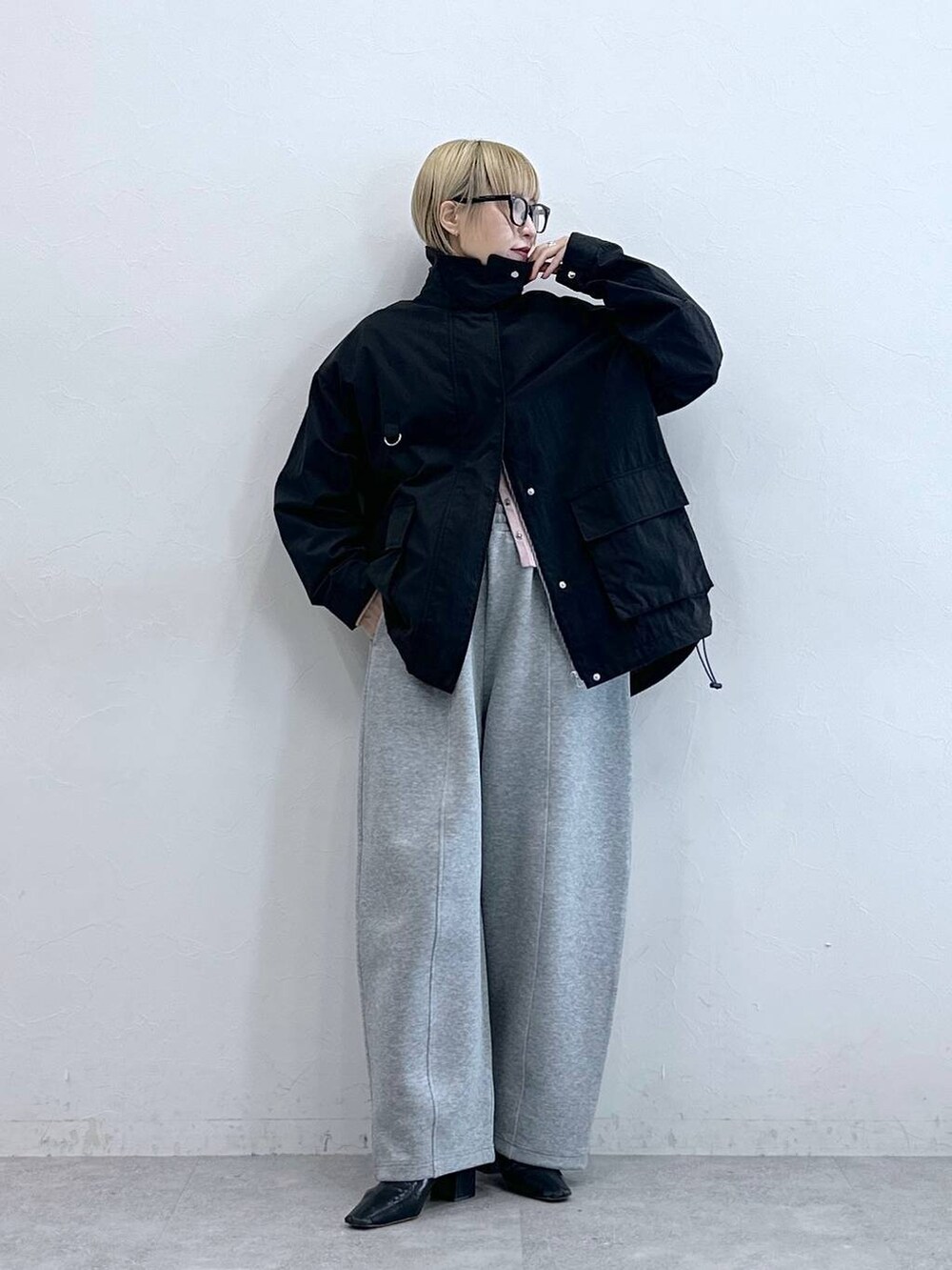 ブラック系のブルゾン、グレー系のスウェットパンツ、グレー系のメガネを着用したレディースの秋コーディネートの2枚目の写真