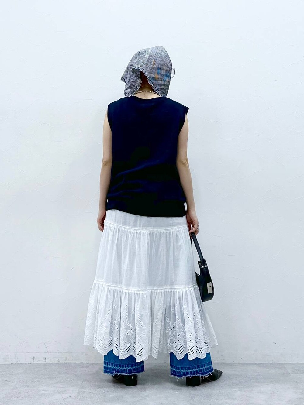 ブルー系のデニムパンツ、ブルー系のベスト、ホワイト系のタンクトップを着用したレディースの春コーディネートの6枚目の写真