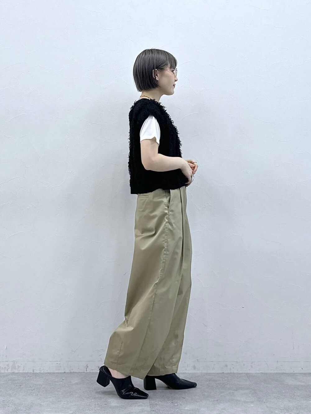 ベージュ系のチノパンツ、ホワイト系のTシャツ/カットソー、ブラック系のベストを着用したレディースの春コーディネートの5枚目の写真