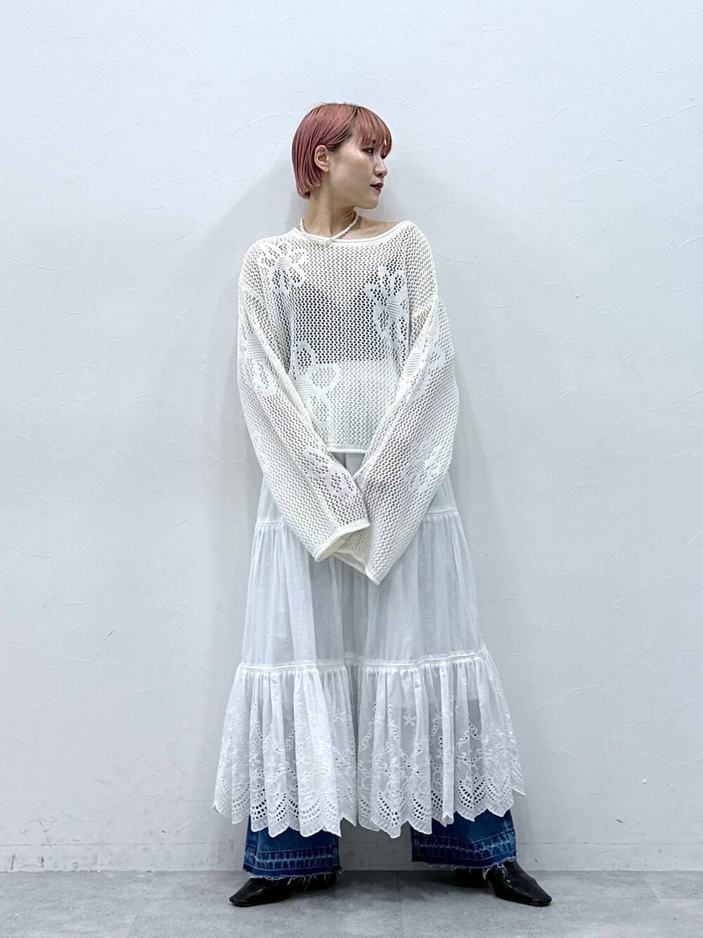 ブルー系のデニムパンツ、ホワイト系のニット/セーター、ホワイト系のスカートを着用したレディースの春コーディネートの5枚目の写真