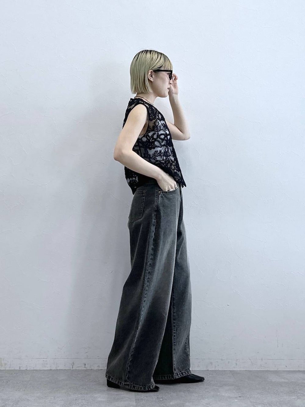 グレー系のデニムパンツ、ブラック系のベスト、ホワイト系のブラジャーを着用したレディースの夏コーディネートの5枚目の写真