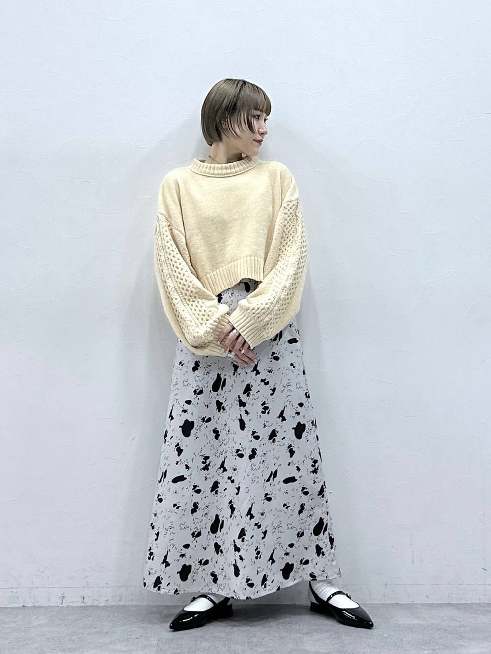 ホワイト系のニット/セーター、ブラウン系のスカート、ブラック系のパンプスを着用したレディースの冬コーディネートの2枚目の写真