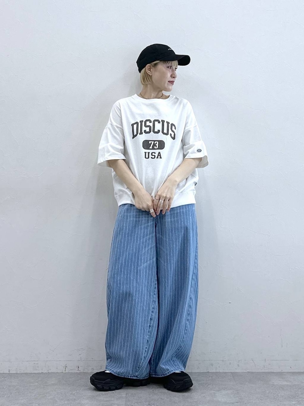 ホワイト系のTシャツ/カットソー、ブラック系のサンダル、ブルー系のデニムパンツを着用したレディースの春コーディネートの3枚目の写真