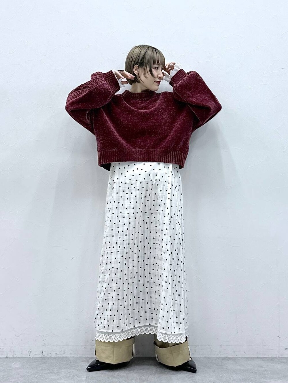 レッド系のニット/セーター、ブラック系のパンプス、ベージュ系のチノパンツを着用したレディースの冬コーディネートの4枚目の写真