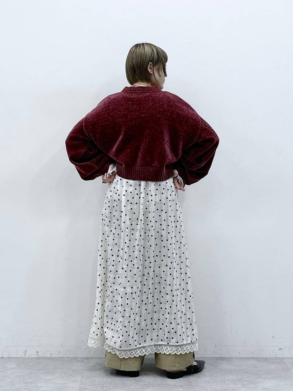 レッド系のニット/セーター、ブラック系のパンプス、ベージュ系のチノパンツを着用したレディースの冬コーディネートの7枚目の写真