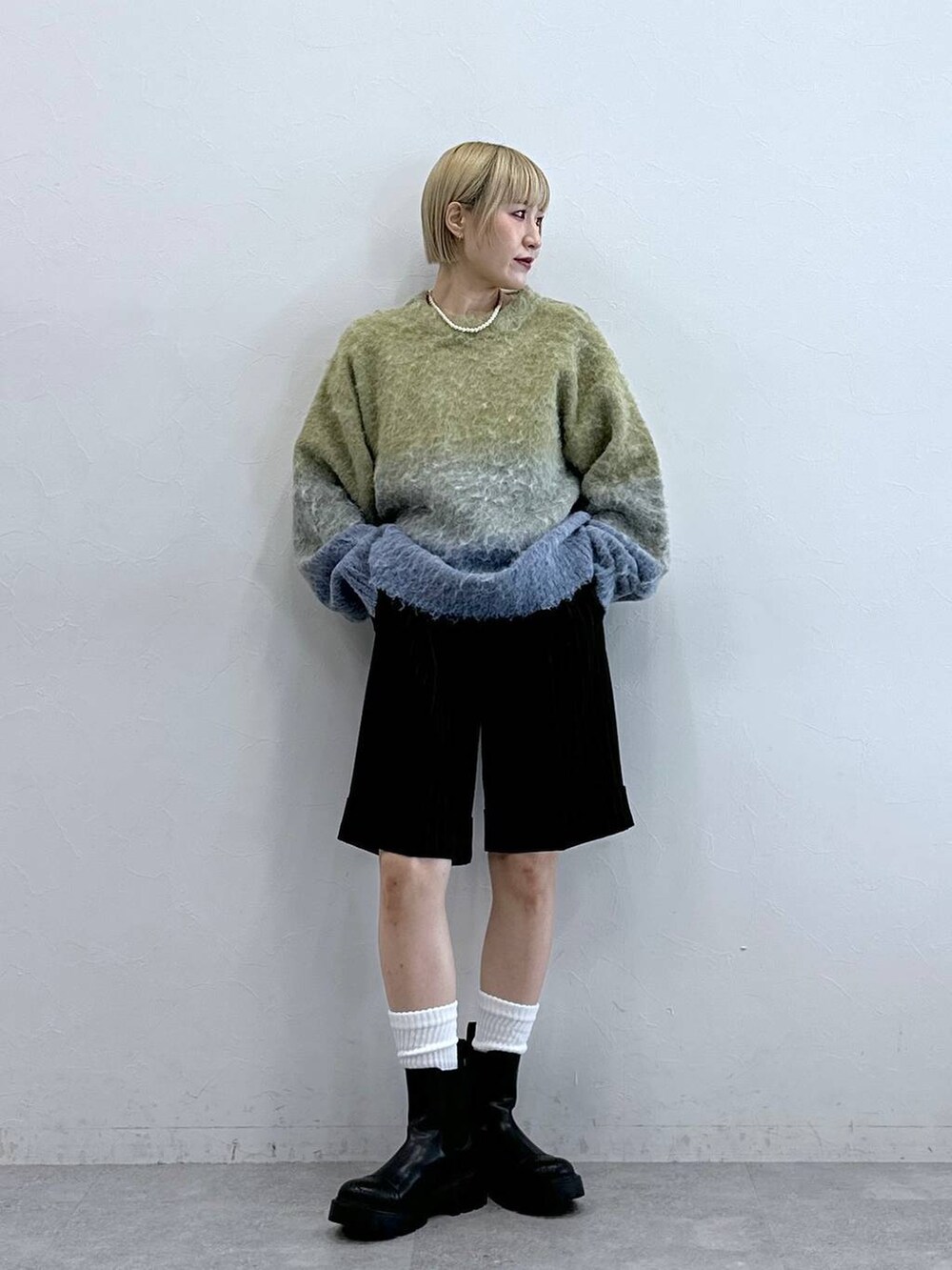 ブラウン系のスラックス、ブラック系のブーツ、イエロー系のニット/セーターを着用したレディースの秋コーディネートの6枚目の写真