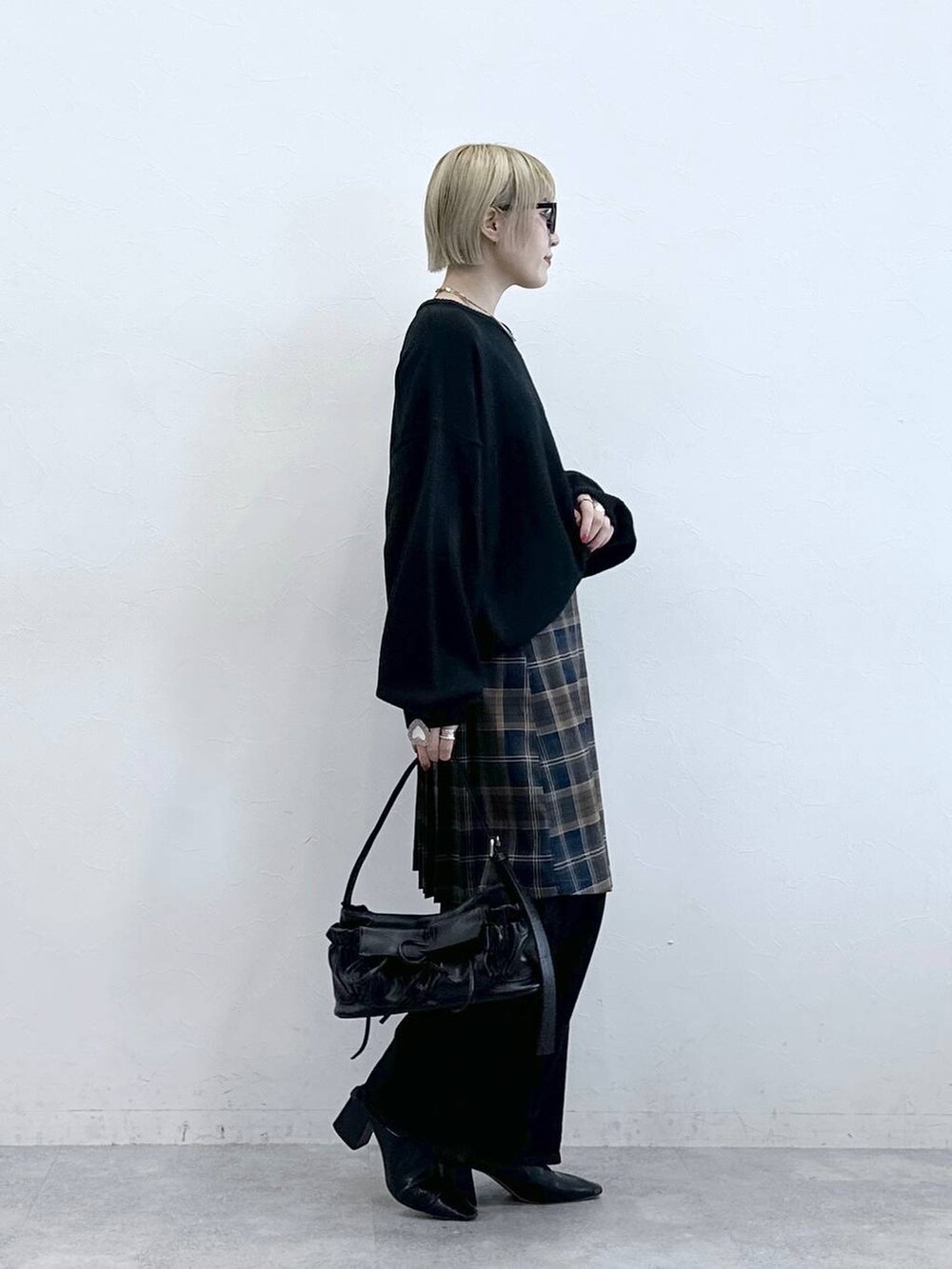 ブラック系のニット/セーター、ブラック系のデニムパンツ、ブラウン系のスカートを着用したレディースの秋コーディネートの4枚目の写真