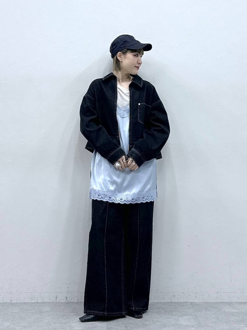 ブラック系のデニムジャケット、ブラック系のデニムパンツ、ブルー系のキャミソールを着用したレディースの冬コーディネートの3枚目の写真